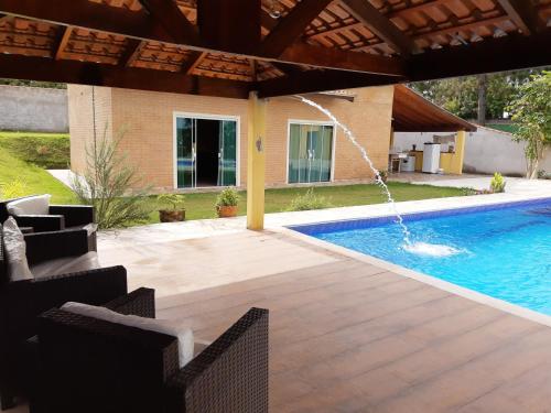 a swimming pool with a patio and a water fountain at Chácara Paiva in Jarinu