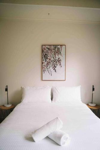 a white bed with white pillows on top of it at The Treehouse Ocean Grove in Ocean Grove