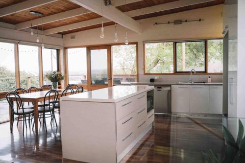 a large kitchen with a table and chairs and windows at The Treehouse Ocean Grove in Ocean Grove