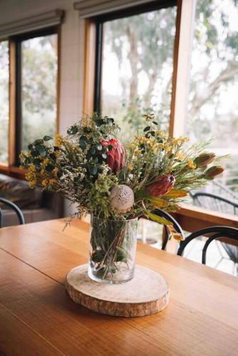 a vase filled with flowers on a wooden table at The Treehouse Ocean Grove in Ocean Grove