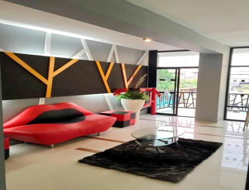 a living room with a red couch and a glass table at Win Hotel Phayao in Phayao