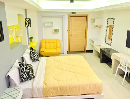 a bedroom with a large bed and a yellow chair at Win Hotel Phayao in Phayao