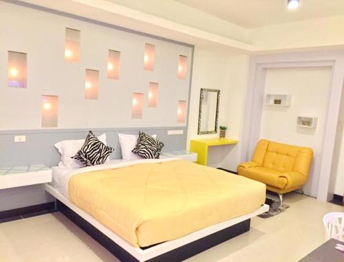 a bedroom with a bed and a yellow chair at Win Hotel Phayao in Phayao
