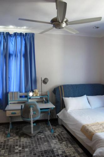 a bedroom with a bed and a desk with a ceiling fan at Penang Batu Ferringhi Beach Bungalow Villa in Batu Ferringhi