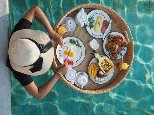 een vrouw met een hoed naast een tafel vol eten bij Avery Le Nixsun Villas Ungasan with Free access to Gym center by Waringin Hospitality in Uluwatu