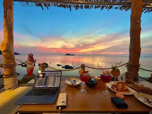 a laptop on a table with a view of the ocean at Siam Cookies Cottage in Haad Pleayleam