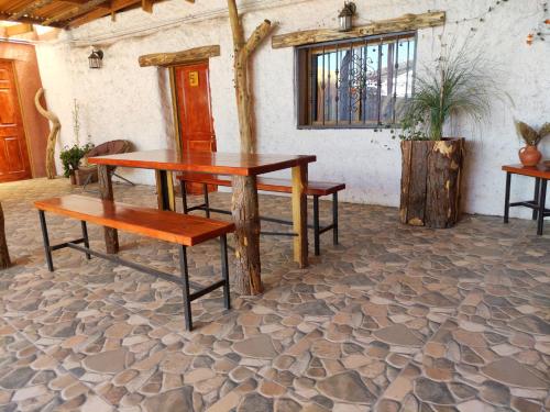 einen Tisch und Bänke in einem Zimmer mit einem Gebäude in der Unterkunft Pirca Hostal in San Pedro de Atacama