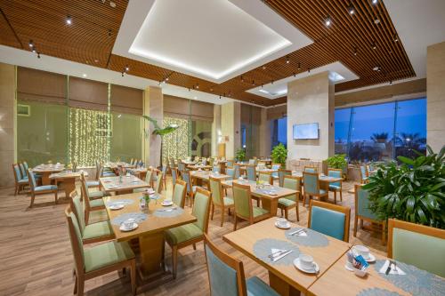a restaurant with wooden tables and chairs and large windows at Diamond Sea Hotel in Da Nang
