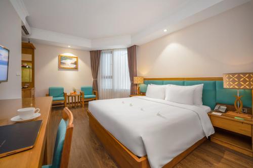 a hotel room with a large bed and a desk at Diamond Sea Hotel in Da Nang