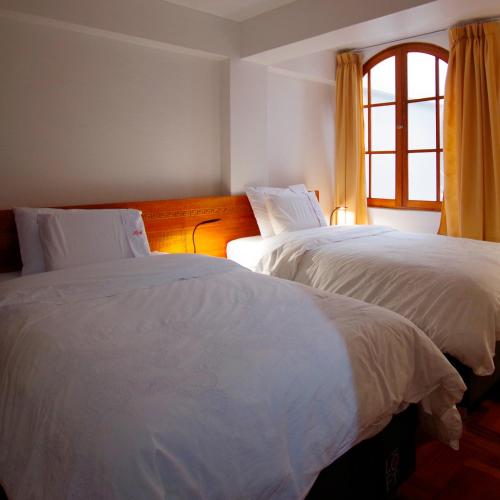 two white beds in a room with a window at Akilpo Home in Huaraz