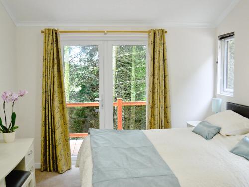 ein Schlafzimmer mit einem Bett und einem großen Fenster in der Unterkunft Ash Lodge in Clatworthy