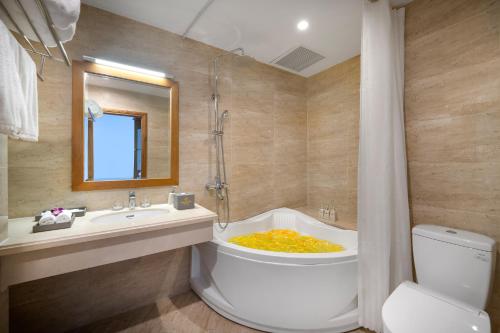 a bathroom with a tub with a toilet and a sink at Diamond Sea Hotel in Danang