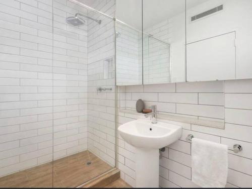 a white bathroom with a sink and a mirror at Modern Beach Oasis in Elwood Village in Melbourne