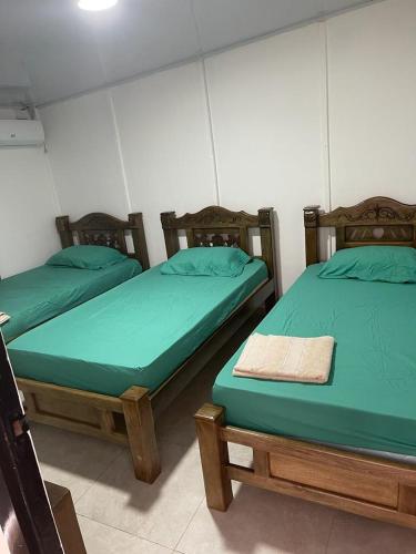 - 2 lits dans une chambre avec des draps verts dans l'établissement Apartamento Vacacional Riohacha, à Ríohacha