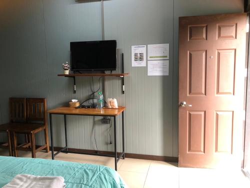 um quarto com uma cama e uma secretária com uma televisão em Green Happy Homestay em Phatthalung