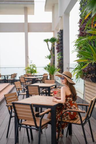 a woman sitting at a table in a restaurant at Diamond Sea Hotel in Da Nang