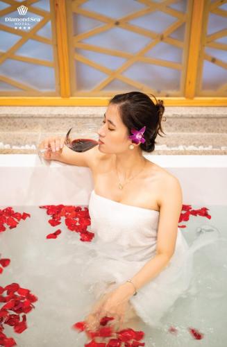 a woman in a bathtub filled with red roses at Diamond Sea Hotel in Da Nang