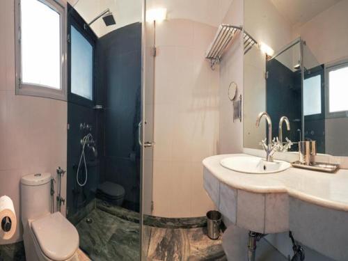 a bathroom with a sink and a shower and a toilet at Haveli Hauz Khas in New Delhi