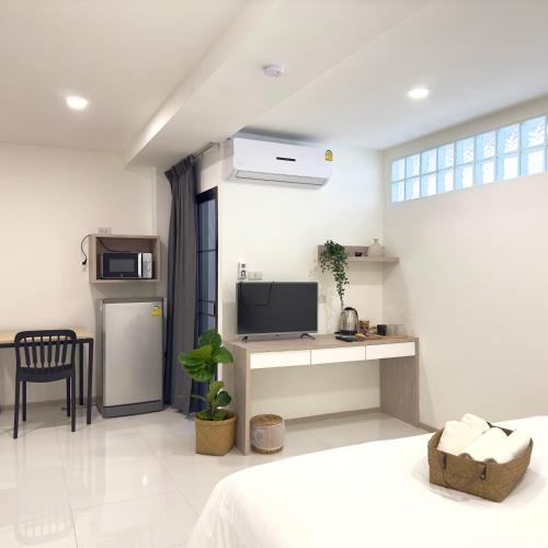 a bedroom with a bed and a desk with a tv at Darin Chiangmai Hotel and Residence in Chiang Mai