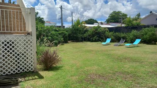 two blue chairs in a yard with a fence at Le Moule Location saisonnière Bel appartement in Le Moule