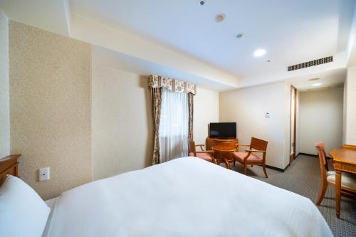 a hotel room with a bed and a desk and a television at KOKO HOTEL Nagoya Sakae in Nagoya