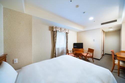 a hotel room with a bed and a desk and a television at KOKO Hotel Nagoya Sakae in Nagoya