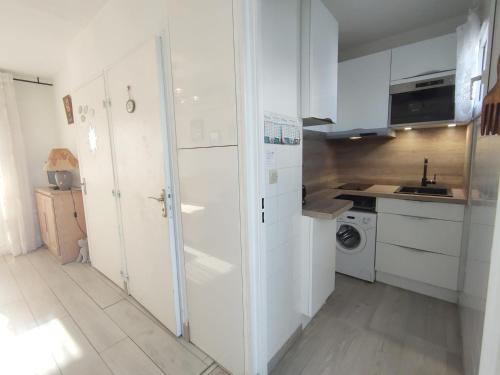 une cuisine avec des armoires blanches et une laveuse et une sécheuse dans l'établissement T1 au calme avec clim et parking privé - FR-1-503-171, à Balaruc-les-Bains