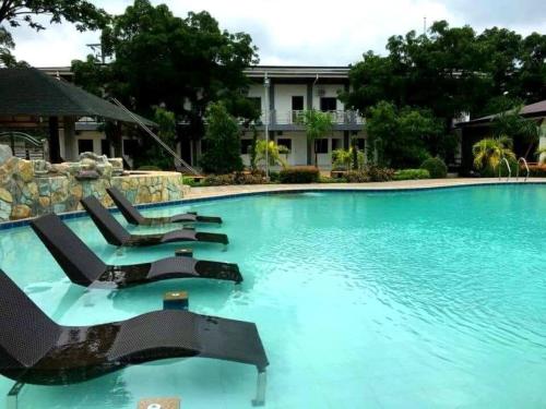 a swimming pool with lounge chairs in front of a building at Floating Sanctuary Resort by Cocotel in Bulacan