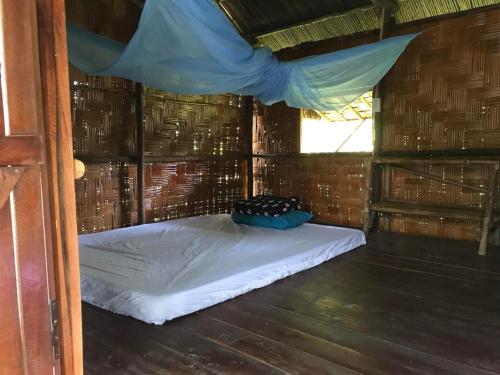 Nui Tuong Village Stay في Tân Phú: سرير في غرفة صغيرة مع نافذة