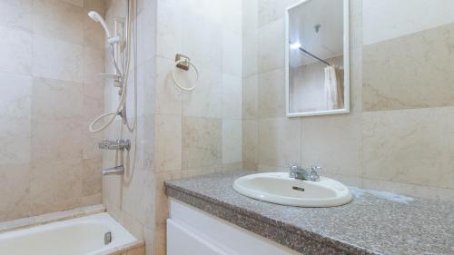 La salle de bains est pourvue d'un lavabo, d'une douche et d'une baignoire. dans l'établissement Sunnette Tower Makati, à Manille