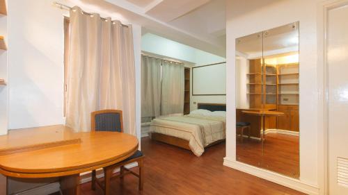 Cette chambre comprend une table, un lit et un bureau. dans l'établissement Sunnette Tower Makati, à Manille