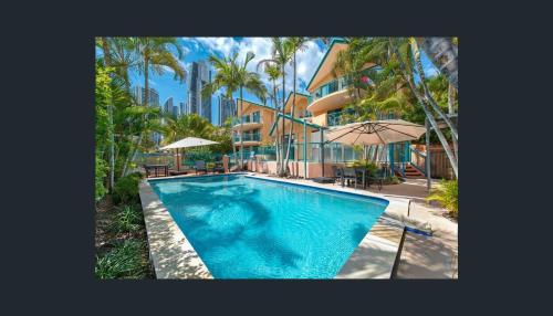 a swimming pool in front of a building with palm trees at Karana Palms Resort in Gold Coast