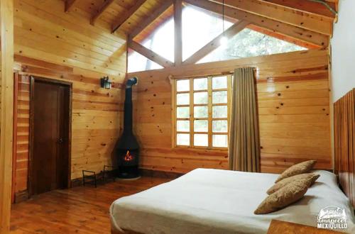 una camera con un letto in una cabina di legno di AMANECER EN MEXIQUILLO - Cabaña encantadora y enorme a La Ciudad