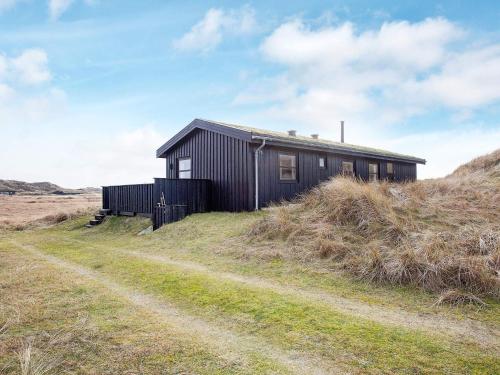 a small black house on a hill with a dirt road at 6 person holiday home in Pandrup-By Traum in Pandrup