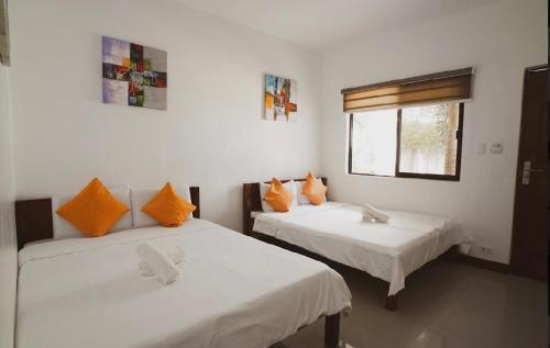 Zimmer mit 2 Betten und orangefarbenen Kissen in der Unterkunft Mountain View Garden Inn Coron in Coron