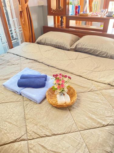 a basket of towels and flowers on a bed at Kp. เพลส หลวงแพ่ง (Kp. Place Luang Phaeng) in Ban Bang Bo