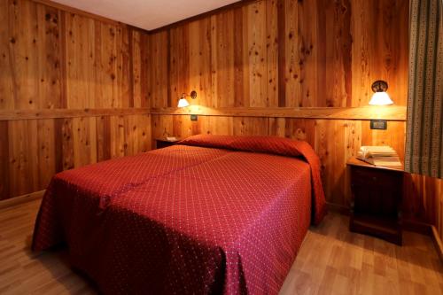 a bedroom with a red bed with wooden walls at Valley Vacanze in Brusson