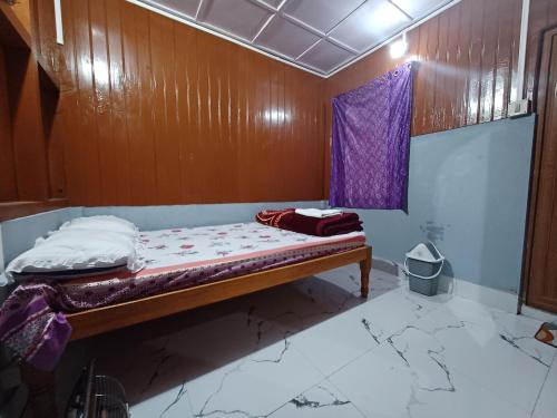 a bed in a room with a purple curtain at Odyssey Stays Siikhe Lake in Hāpoli