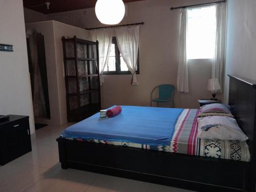 a bedroom with a bed with a blue comforter and a window at Harmony House Stay in Padangbai