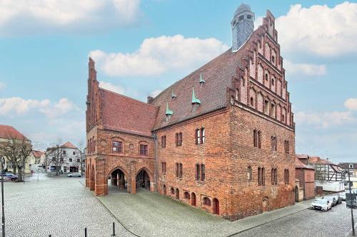 a large brick building with a tower on a street at Chic Apartment in Jüterbog in Jüterbog