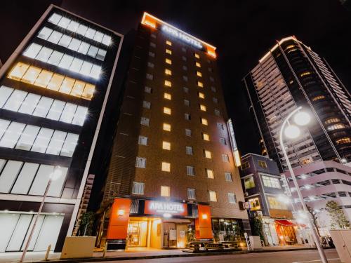 two tall buildings in a city at night at APA Hotel Nagoya Fushimi Ekikita in Nagoya