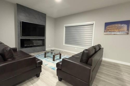 uma sala de estar com 2 cadeiras de couro e uma televisão de ecrã plano em 3 Bedroom Single Family Home em Edmonton