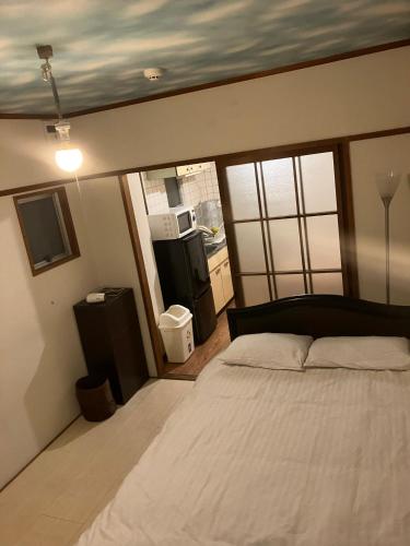 a bedroom with a large bed and a kitchen at Casa Viento Stay Inn in Hiroshima