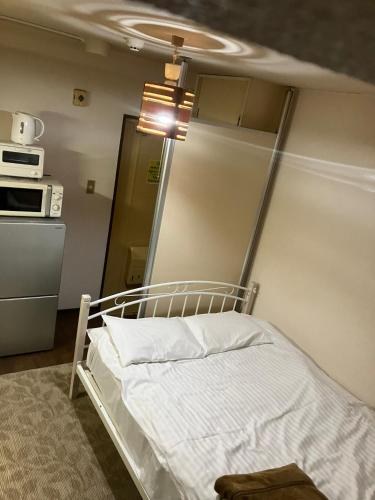 a bed in a room with a kitchen at Casa Viento Stay Inn in Hiroshima