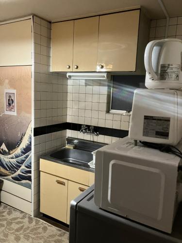 a kitchen with a refrigerator and a microwave at Casa Viento Stay Inn in Hiroshima