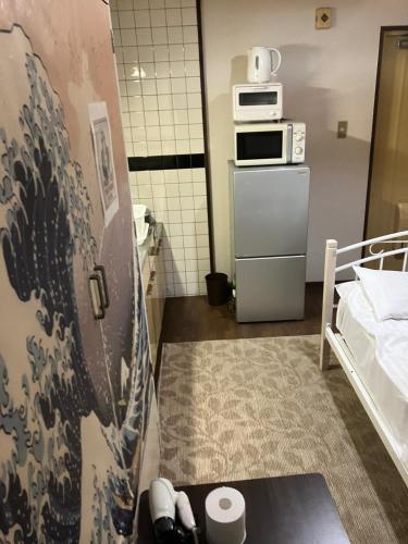 a small room with a bed and a microwave at Casa Viento Stay Inn in Hiroshima