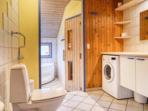 uma casa de banho com um WC e uma máquina de lavar roupa em Holiday home Hjørring VIII em Hjørring