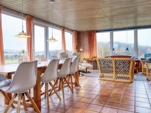 a dining room with a table and chairs and windows at 12 person holiday home in Hjørring-By Traum in Hjørring
