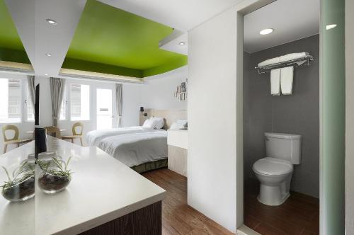 a bathroom with a bed and a toilet in a room at Papersun Hotel in Taipei