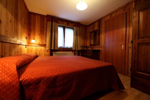 a bedroom with a bed with an orange comforter at Valley Vacanze in Brusson